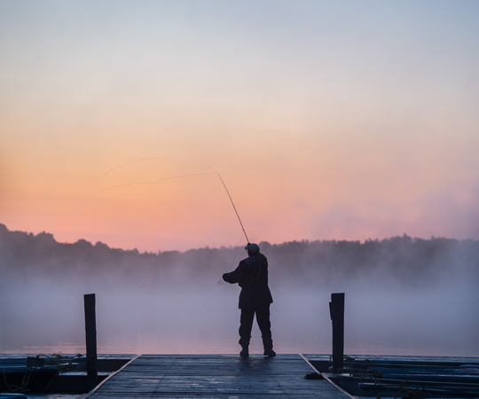 Découvrir la région Un pêcheur lance sa ligne au bout d'un quai à Lanaudière.